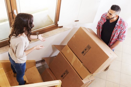 A removals team carefully carrying furniture through a narrow Soho building entrance